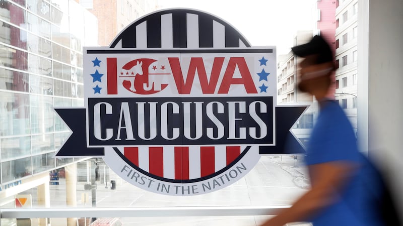 A pedestrian walks past a sign for the Iowa Caucuses on a downtown skywalk, in Des Moines,...