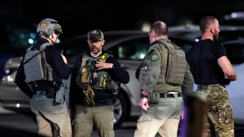 State police and an FBI bomb technician stand at a staging area in the parking lot of New...