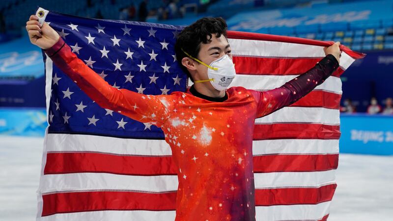 Nathan Chen, of the United States, holds his national flag as he celebrates after winning the...