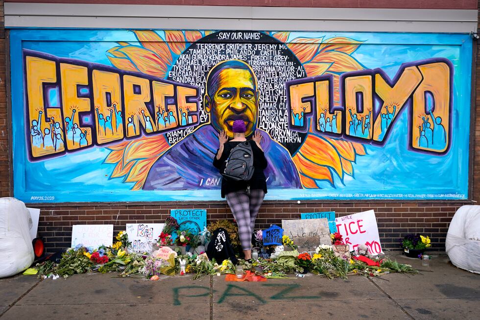 FILE - Damarra Atkins pays respect to George Floyd at a mural at George Floyd Square in...