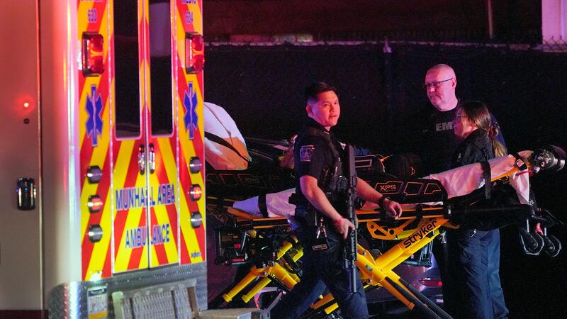 A law enforcement officer walks past an EMS crew on the scene at Kennywood Park, an amusement...